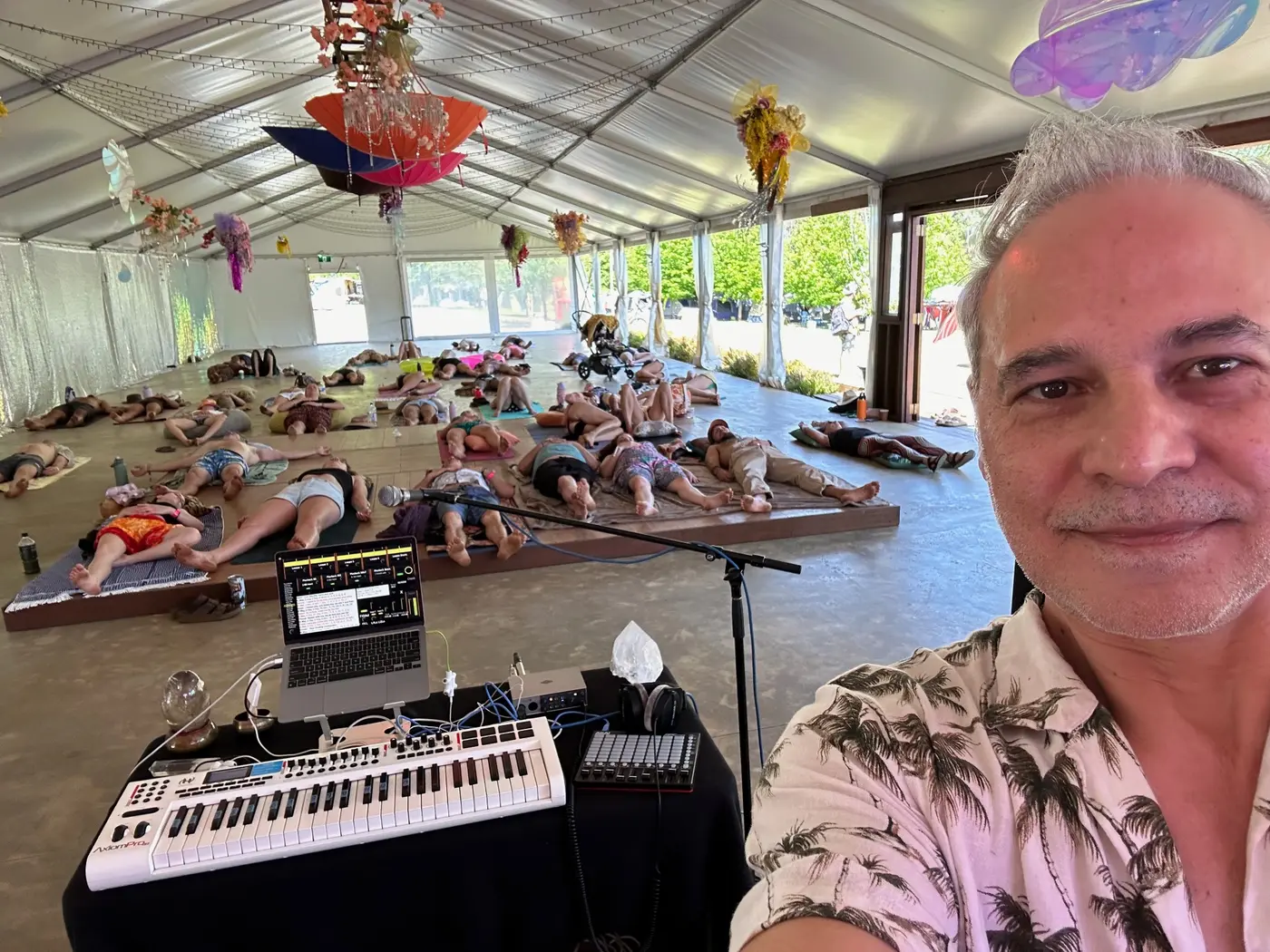Sam Cutri at his performance station with a festival audience resting throughout a pavilion