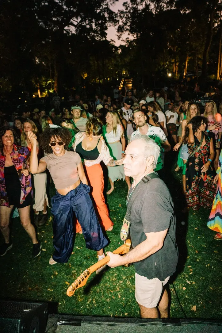 Sam Cutri playing guitar with Radio Coco among an outdoor festival audience