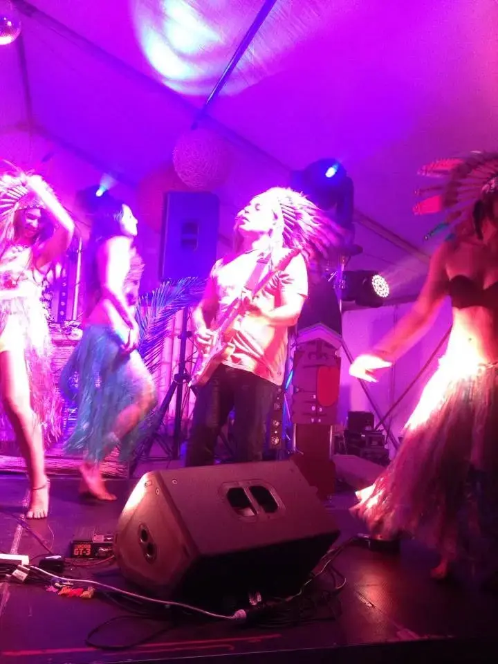 Sam Cutri playing guitar with Radio Coco and dancers under vivid stage lighting