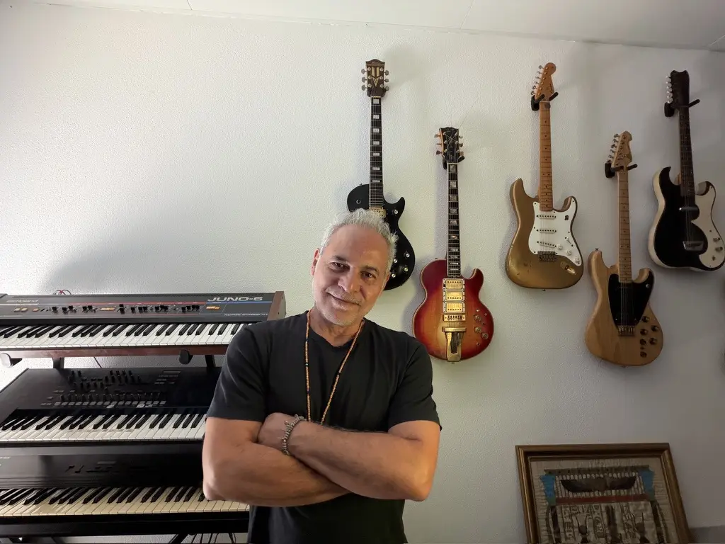 Sam Cutri surrounded by guitars and keyboards in his music room